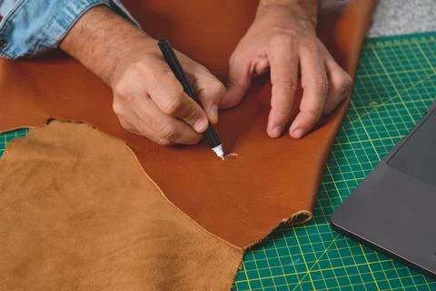 Shoemaker designing leather pieces using silver pen in workshop Stock Photos