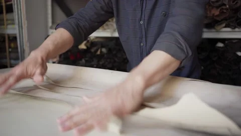 Shoemaker examining beige textile at workbench Stock Footage 142547556