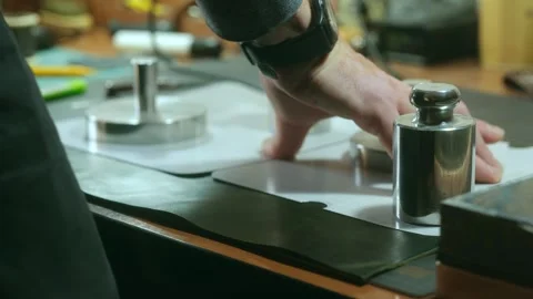 Shoemaker gluing leather pieces using heavy weights Stock Footage 296748966
