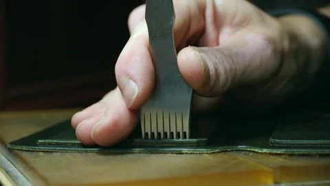 Shoemaker making stitching holes with punching tool Stock Footage 296551910