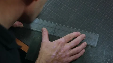 Shoemaker measuring and cutting leather with ruler and cutter Video stock 296748435