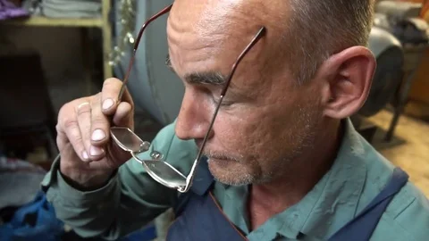 The shoemaker puts on his glasses and starts its work Stock Footage 77869716