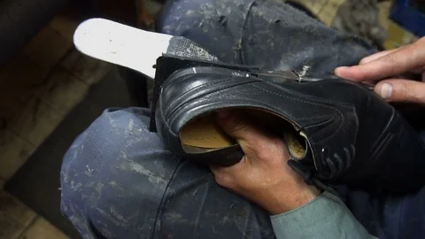 Shoemaker repairing a shoe in workshop 4k cut the taps on the shoes Stock Footage 77876070