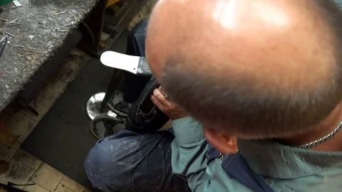 Shoemaker repairing a shoe in workshop 4k cut the taps on the shoes Stock Footage 77876189