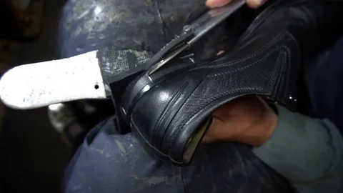 Shoemaker repairing a shoe in workshop 4k cut the taps on the shoes Stock Footage 77876343
