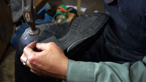 Shoemaker repairing a shoe in workshop 4k nail the heel cap to the heel Vídeos de archivo 77876961