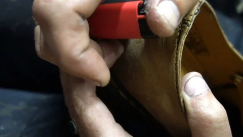 Shoemaker singeing lighter thread after flashing Shoe Stock-Footage 77872763