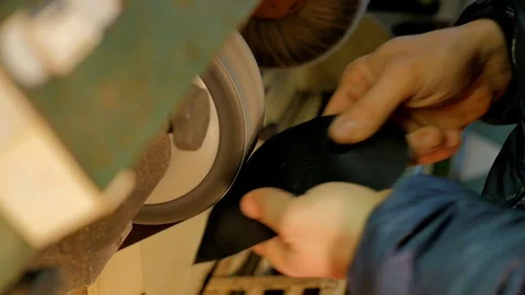 Shoemaker smooths the rubber sole of a woman's shoe Stock Footage 85525555