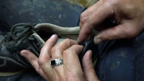The shoemaker sticks a black leather patch on sneakers Stock Footage 77873188