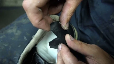 The shoemaker sticks a black leather patch on sneakers Stock Footage 77873361