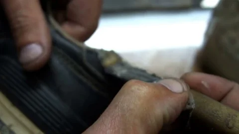 The shoemaker sticks a black leather patch on sneakers Stock Footage 77874369