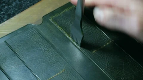 Shoemaker stitching a green leather wallet Stock Footage 296747343