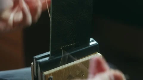 Shoemaker stitching leather belt using awl Stock Footage 296747799