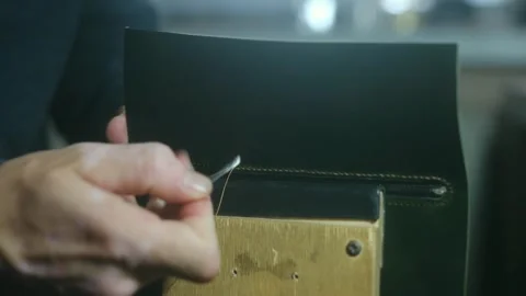 Shoemaker stitching leather with needle and thread Stock Footage 296747688