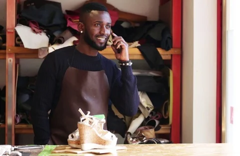 Shoemaker talking on the mobile phone in workshop Stock Footage 104984192