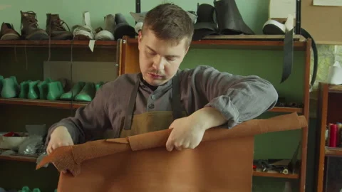 A shoemaker's apprentice rolls a piece of genuine leather into a roll. In the Stock Footage 143725815
