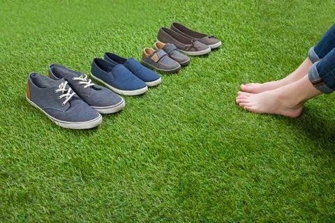Shoes standing  on grass in front of bare legs Stock Photos