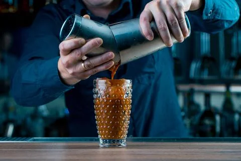 A shoot of bartender standing at the bar counter, preparing a tomato cocktail Stock Photos