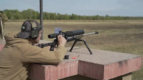 The shooter performs a shooting exercise in a sitting position with a rifle Stock Footage 251632632