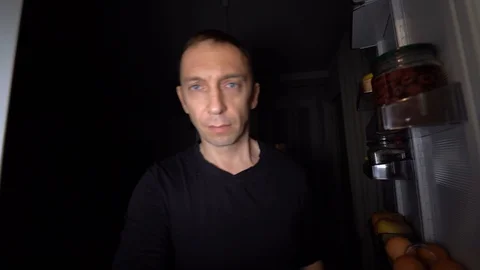 Shooting 4K. A hungry middle-aged man comes to the kitchen at night to eat. Stock Footage 129407261