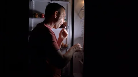 Shooting 4K. A hungry middle-aged man comes to the kitchen at night to eat. Stock Footage 129407388