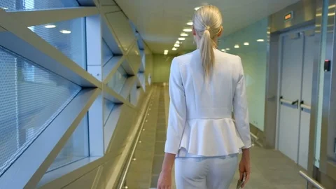 Shooting from back passenger walks down hallway at airport Stock Footage 71644773