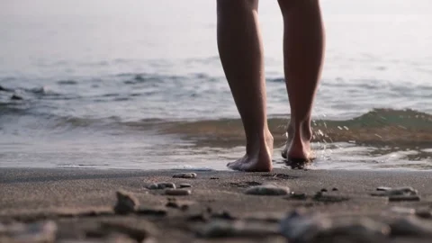 Shooting from behind bare knee-deep human legs walking slowly, measured steps in Stock Footage 216702276