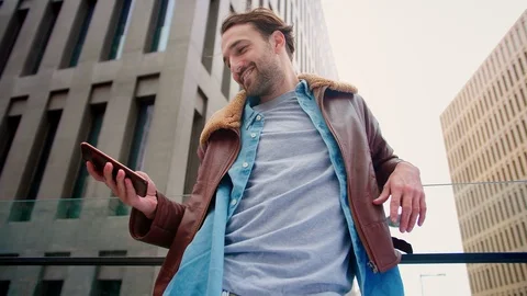 Shooting from below of handsome Hispanic guy standing using cell phone at modern Stock Footage 115910275