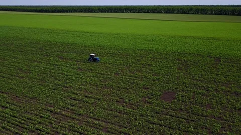 Shooting from drone flying over tractor with harrow system plowing ground on Stock Footage 173678313