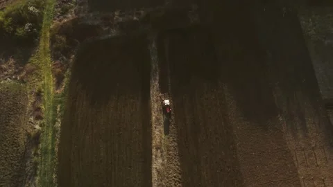 Shooting from drone flying over tractor with harrow system plowing ground on Stock Footage 184439878