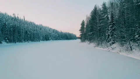 Shooting on a drone. Slow flight over a snow-covered river along the forest. Stock Footage 233768213