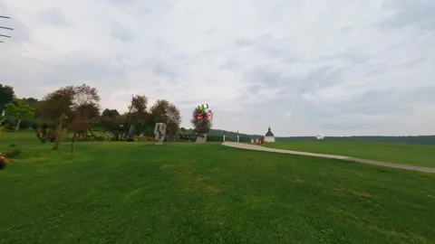 Shooting of fast drone FPV flying through green park with beautiful flower beds Video stock 183465287