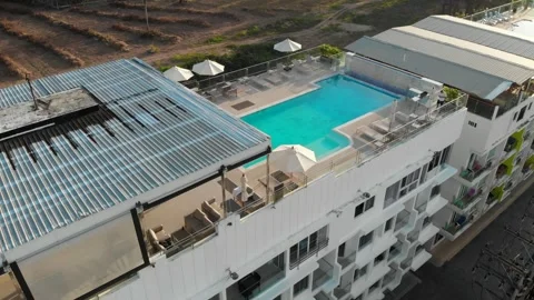 Shooting of a hotel with a rooftop pool, a bar, sunbeds and umbrellas, hills Stock Footage 246844467
