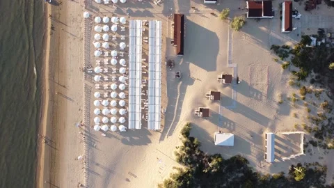 Shooting from a quadcopter beach with umbrellas and deck chairs near a wild beac Video stock 194285545