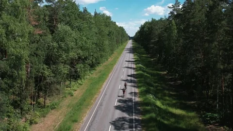 Shooting from a quadrocopter of a man with a backpack on a bicycle that rides 库存影片 222087918