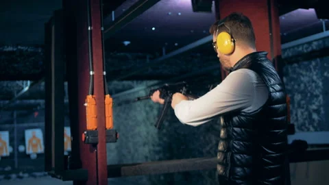Shooting range with a man aiming from his rifle 库存影片 98892515