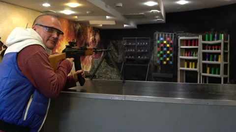 Shooting range. Man in glasses aims and shoots a PK machine gun in the dash at Vidéo 100613715