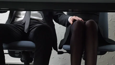Shooting under the table, a young guy in a suit, the boss touches his employee's Stock Footage 89394654