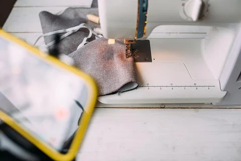 Shooting video of the sewing process, workshop on clothing design on smartphone 库存照片