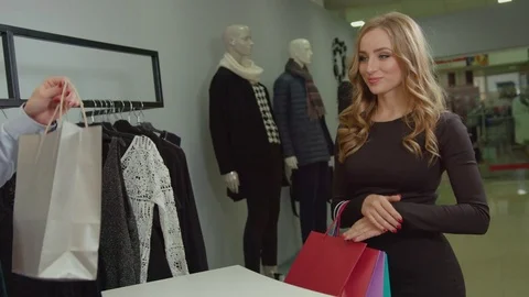 Shop assistant giving a shopping bag to beautiful woman customer in fashion Stock Footage 73962017