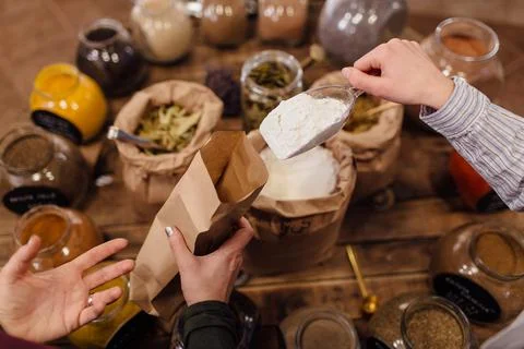 Shop assistant hand only scooping flour for customer in packaging free shop. Stock Photos