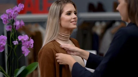 Shop assistant helping customer in clothes shop Stock Footage 121161843