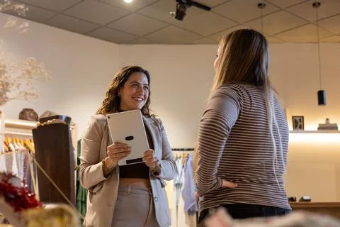 Shop assistant helping customer using digital tablet Stock Photos