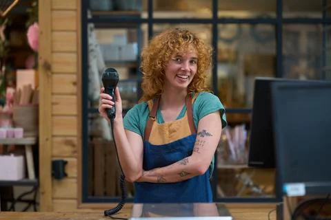 Shop assistant holding barcode scanner at checkout counter Stock Photos