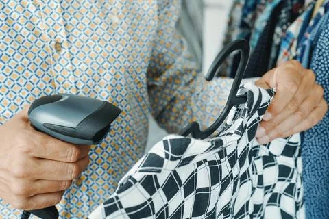 Shop assistant scanning a barcode in a clothes shop using Foto stock