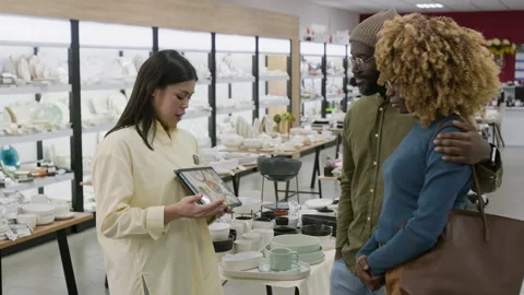 Shop Consultant Recommending New Dinnerware Collection to Couple Stock Footage 321777614