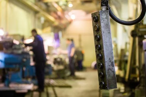 Shop crane control panel box with blurry milling workers in the background Stock Photos