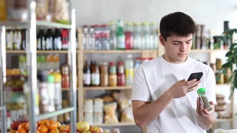 In shop guy scans QR code and take reading seasonings herbs using phone camera Stock Footage 315550351