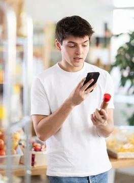 In shop guy scans QR code and take reading chopped red ground pepper using phone Foto stock