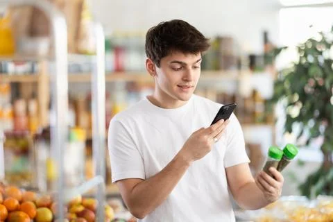 In shop guy scans QR code and take reading seasonings herbs using phone camera Stock-Fotos
